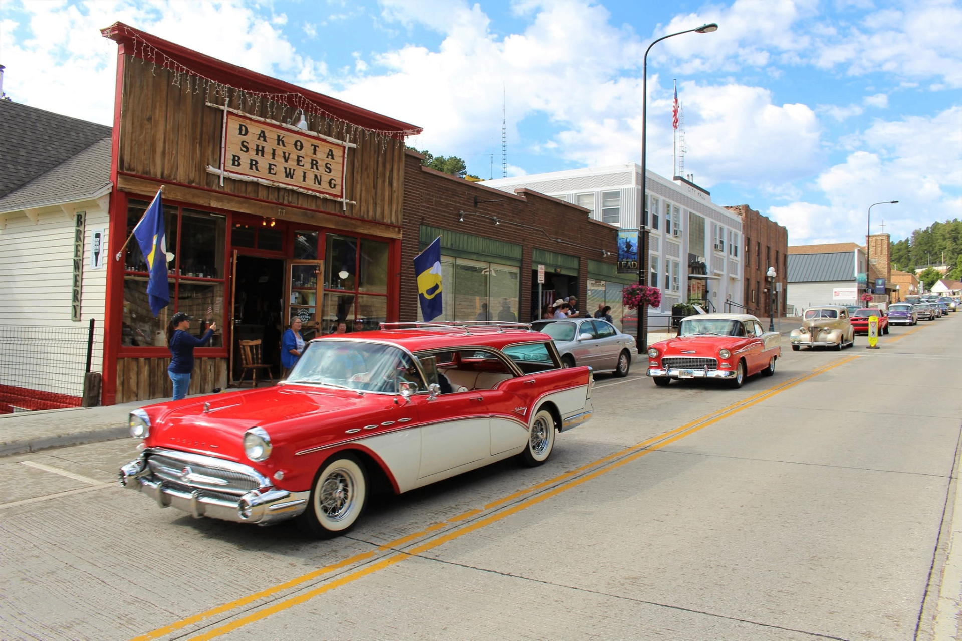 Classic red car passing Dakota Shivers Brewing on Main Street
